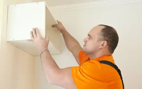 Un homme installe une étagère murale, une étape cruciale pour fixer meuble lourd sur placo.