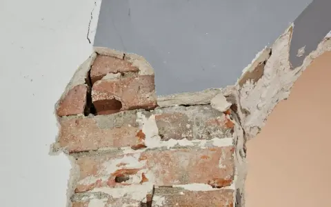 Fissures dans un mur de briques, signe d'une **stabilisation fondation maison sol argileux** nécessaire.