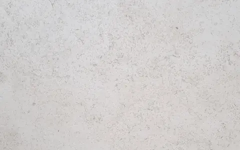 Surface texturée d'enduit chaux chanvre finition lisse, d'une teinte claire et naturelle, évoquant la douceur d'un mur sain.