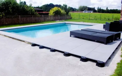 Terrasse de piscine avec dalles sur plots réglables. Le prix au m2 pour ce type de pose est compétitif pour un rendu moderne et pratique.