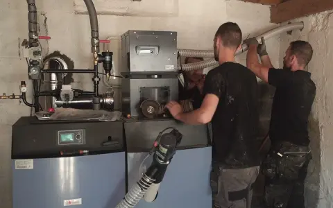 Techniciens installant une nouvelle chaudière, remplaçant une ancienne chaudière fioul. Travaux de chauffage en cours.