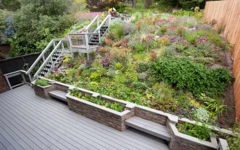 Magnifique aménagement talus raide avec escalier, terrasses et jardinières fleuries. Un jardin luxuriant et coloré.