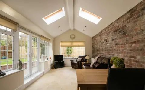 Salon lumineux avec murs en briques apparentes, baies vitrées donnant sur jardin. Idéal pour estimer le prix d'une extension 20m2 en parpaing.
