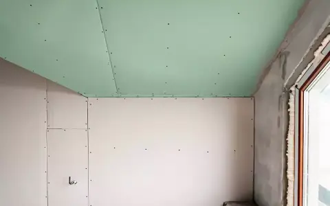 Jonction mur plafond placo, avec un plafond vert et des murs blancs. Travaux de rénovation en cours.