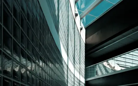 Mur extérieur en pose brique de verre, reflétant la lumière et créant des jeux d'ombres sur la façade moderne.
