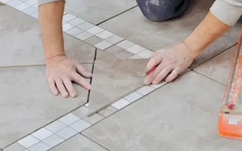 Pose d'une nouvelle dalle pour le calepinage terrasse carrelage, avec un crayon pour marquer la découpe.