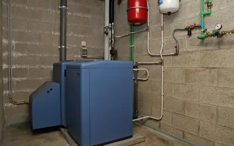 Chaudière fioul bleue dans une chaufferie, avec réservoirs rouge et blanc. Le prix du chauffage fioul est une préoccupation.