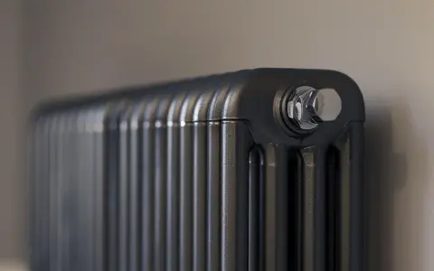 Gros plan sur un radiateur bain d'huile noir, avec un bouchon chromé visible. Un élément clé pour gérer la consommation d'énergie.