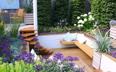 Magnifique terrasse en bois avec banquette intégrée, escalier en colimaçon et fleurs violettes. Idéal pour fabriquer banquette bois terrasse.