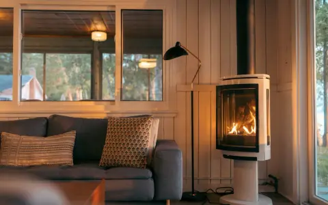 Un poêle à bois moderne, avec un feu vif, est placé à distance du mur en placo, créant une ambiance chaleureuse.
