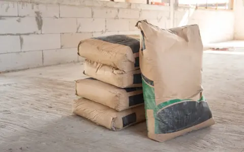 Pile de sacs de ciment sur un chantier. Pour estimer combien de sac de ciment pour 1m3, il faut connaître le dosage.