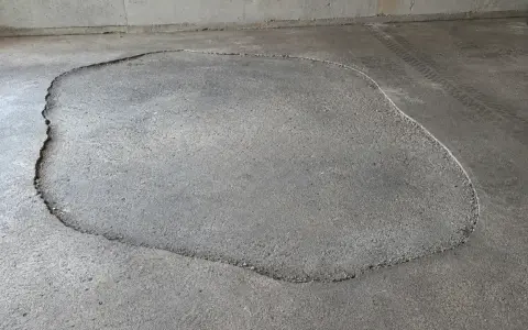Une large fissure délimite une zone de la terrasse qui s'affaisse, révélant le gravier en dessous.