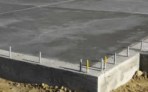 Dalle de béton fraîchement coulée, montrant la base d'une fondation et l'épaisseur de la semelle en béton.