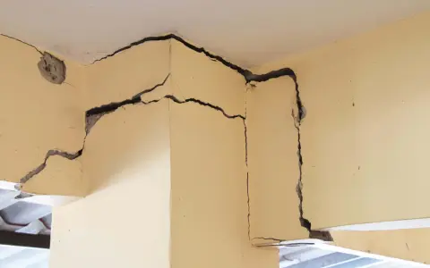 Détail d'une **micro fissure maison** sur un coin de mur en béton, révélant la structure interne.