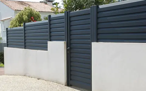 Devis mur de clôture en parpaing : mur bas en béton avec portail gris anthracite et claustras modernes.