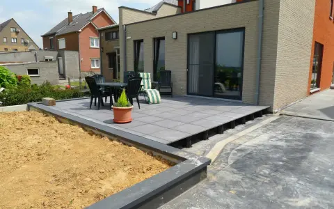 Une terrasse moderne en cours de création, avec des dalles grises surélevées par des plots. Un espace extérieur prêt à être aménagé.