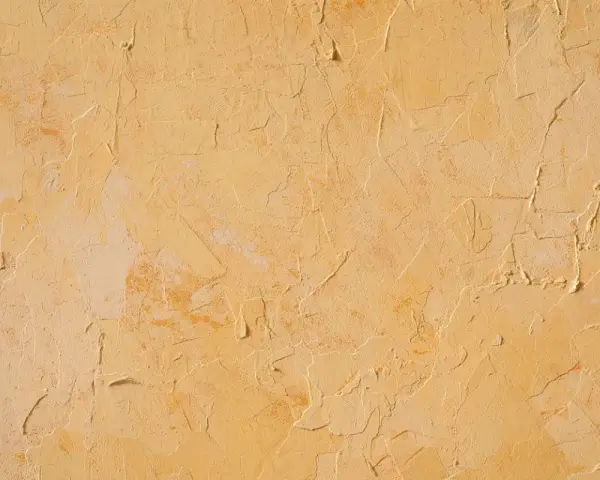 Texture d'un enduit taloché ou gratté, aux nuances chaudes de jaune et d'ocre, évoquant un mur ancien patiné par le temps.