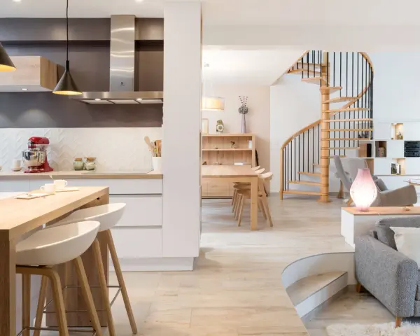 Cuisine moderne avec îlot, escalier hélicoïdal et salon. Cette maison, aux caractéristiques des années 70, allie confort et design.