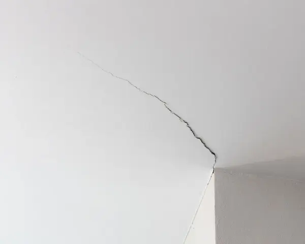Fissure visible sur un joint de placo au plafond, indiquant la nécessité de réparer.