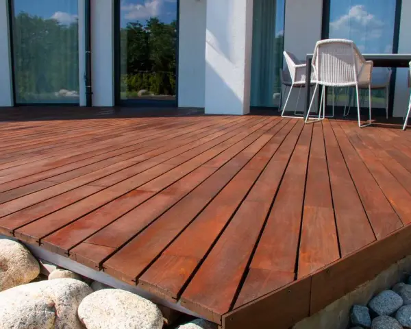 Belle terrasse en bois sur plot, avec des meubles de jardin et des rochers.