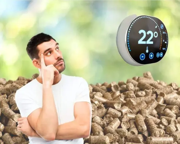 Un homme réfléchit devant un tas de granulés de bois, un thermostat intelligent Netatmo affiche 22°.