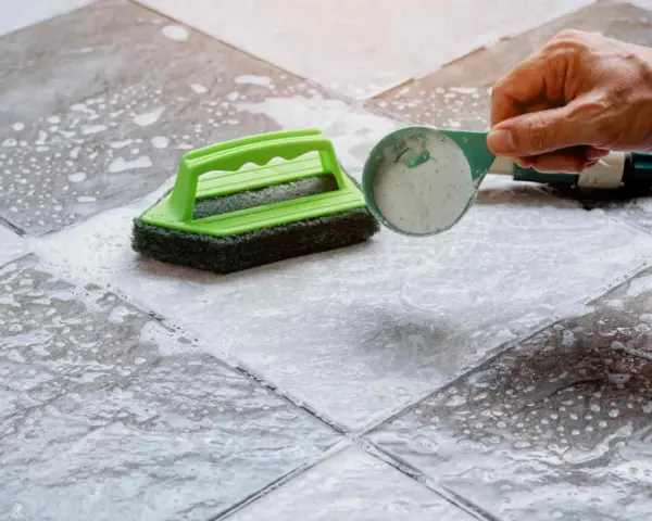 Nettoyer carrelage extérieur antidérapant avec une brosse et une poudre nettoyante.