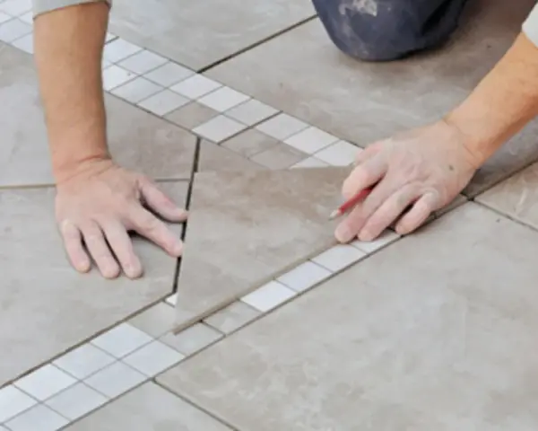 Pose d'une nouvelle dalle pour le calepinage terrasse carrelage, avec un crayon pour marquer la découpe.