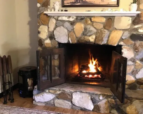 Un feu crépite dans une cheminée en pierres. Quel parement derrière poêle à bois, avec des accessoires de cheminée à gauche.