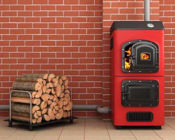 Une chaudière biomasse, c'est quoi ? Une chaudière rouge vif avec du bois de chauffage à côté, prête à chauffer.