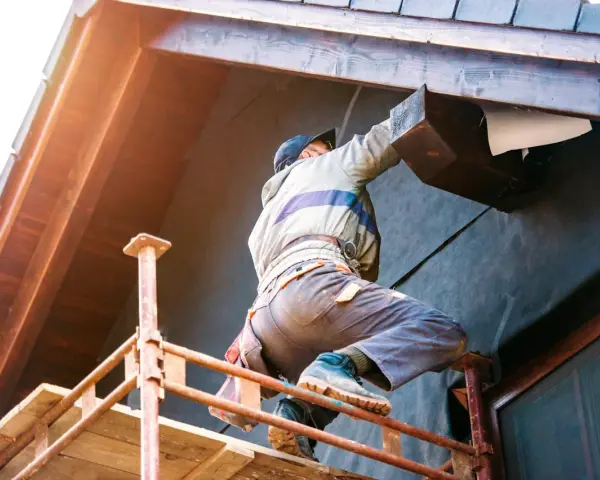 Un ouvrier sur un échafaudage installe l'isolation extérieur facade d'une maison, protégeant la structure en bois.