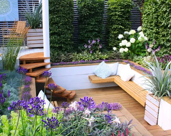 Magnifique terrasse en bois avec banquette intégrée, escalier en colimaçon et fleurs violettes. Idéal pour fabriquer banquette bois terrasse.
