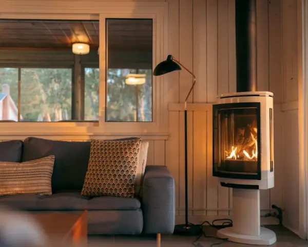Un poêle à bois moderne, avec un feu vif, est placé à distance du mur en placo, créant une ambiance chaleureuse.