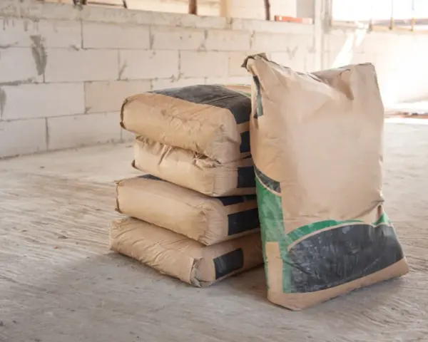 Pile de sacs de ciment sur un chantier. Pour estimer combien de sac de ciment pour 1m3, il faut connaître le dosage.