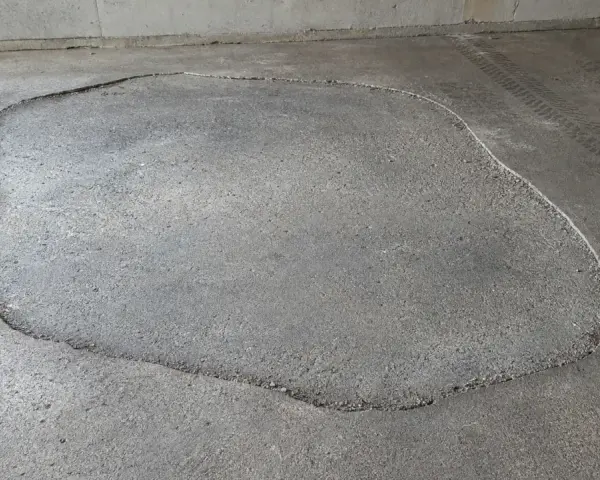 Une large fissure délimite une zone de la terrasse qui s'affaisse, révélant le gravier en dessous.