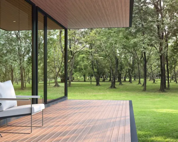 Une terrasse moderne avec un revêtement de terrasse en résine, offrant une vue paisible sur une forêt verdoyante. Un fauteuil confortable invite à la détente.