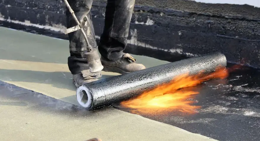 Pose d'une membrane bitumineuse sur une terrasse. Le prix de l'étanchéité d'une terrasse carrelée dépend de la technique utilisée.