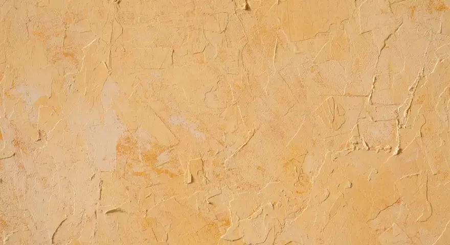 Texture d'un enduit taloché ou gratté, aux nuances chaudes de jaune et d'ocre, évoquant un mur ancien patiné par le temps.