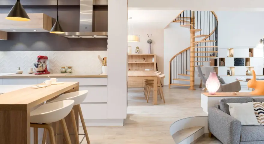 Cuisine moderne avec îlot, escalier hélicoïdal et salon. Cette maison, aux caractéristiques des années 70, allie confort et design.