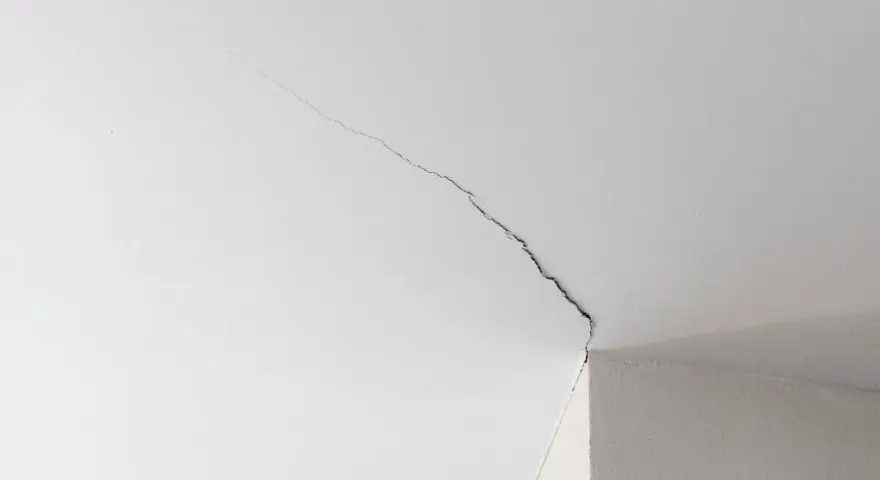Fissure visible sur un joint de placo au plafond, indiquant la nécessité de réparer.