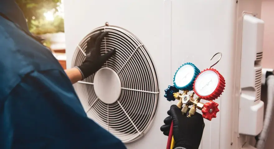 Technicien effectuant l'entretien d'une pompe à chaleur air/air, vérifiant la pression avec un manomètre.