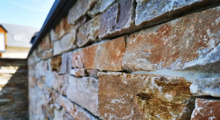 Gros plan sur une pose de pierre de parement extérieur aux teintes chaudes et naturelles, créant une texture rustique et élégante.