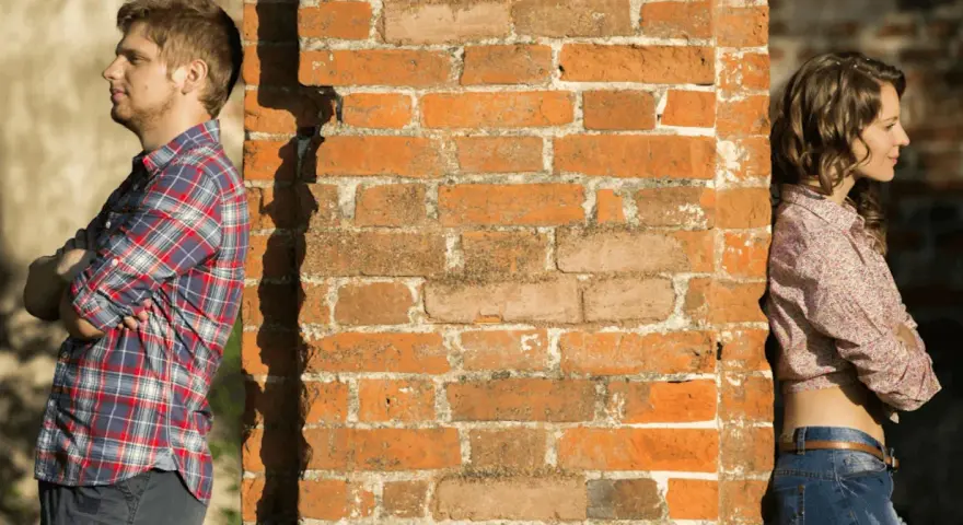 Un homme et une femme se tournent le dos, appuyés contre un mur de briques. Peut-on fixer quelque chose sur un mur mitoyen ?