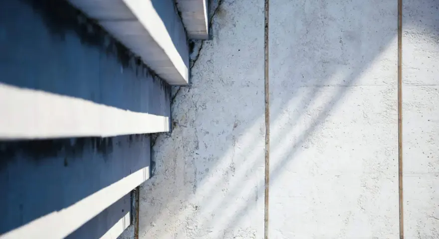 Ombre et lumière sur un mur en béton cellulaire, texture brute et lignes architecturales.