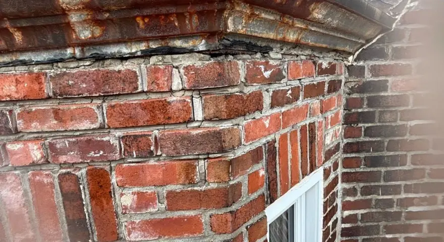 Le joint brique extérieur montre des signes de dégradation, avec des fissures et des effritements. La corniche rouillée au-dessus semble aussi avoir besoin d'attention.