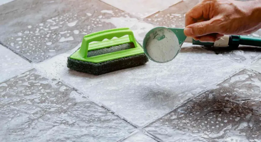 Nettoyer carrelage extérieur antidérapant avec une brosse et une poudre nettoyante.