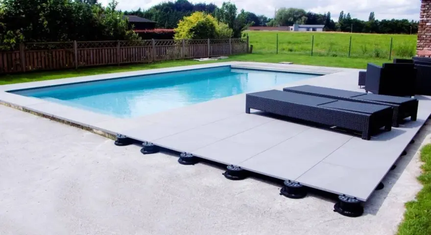 Terrasse de piscine avec dalles sur plots réglables. Le prix au m2 pour ce type de pose est compétitif pour un rendu moderne et pratique.