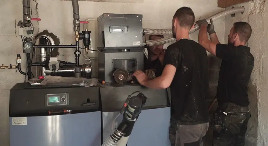 Techniciens installant une nouvelle chaudière, remplaçant une ancienne chaudière fioul. Travaux de chauffage en cours.