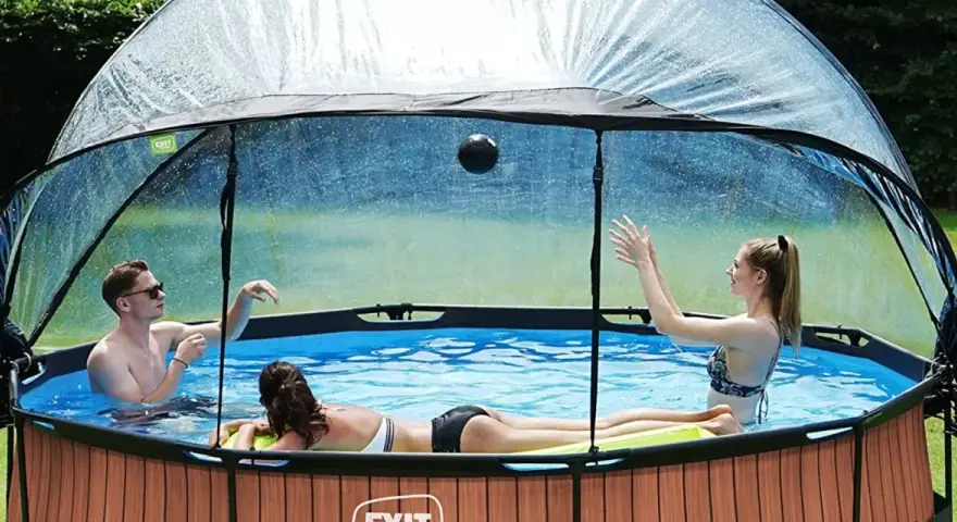 Trois personnes jouent dans une piscine hors sol sous un abri transparent. Idéal pour savoir comment fabriquer un abri piscine hors sol.
