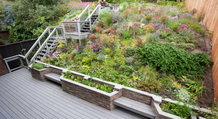 Magnifique aménagement talus raide avec escalier, terrasses et jardinières fleuries. Un jardin luxuriant et coloré.