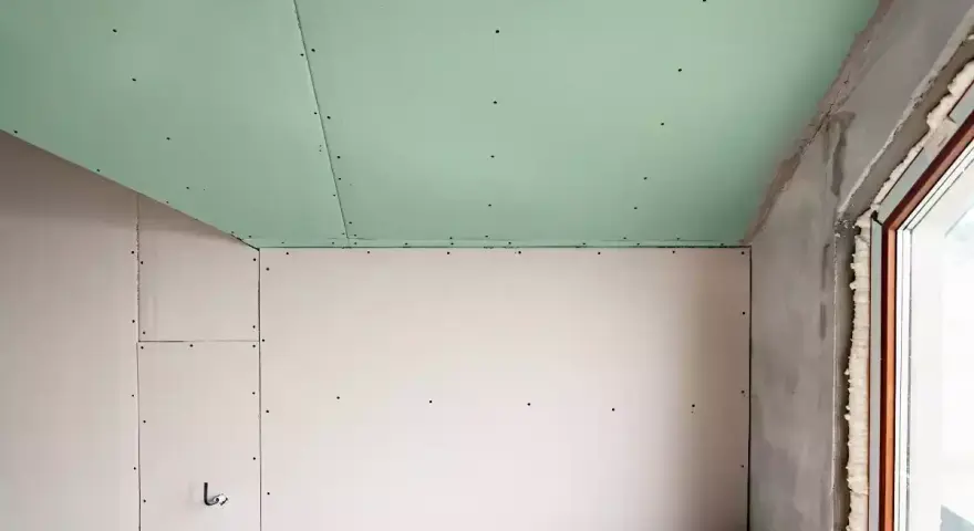 Jonction mur plafond placo, avec un plafond vert et des murs blancs. Travaux de rénovation en cours.